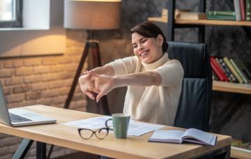 Mujer sentada en el escritorio de trabajo crujiendo sus nudillos
