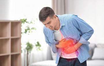 Qué es la gastritis aguda, síntomas y tratamiento Joven con un dolor agudo en el estómago provocado por una gastritis