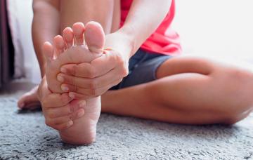 Persona que se toca el pie con fascitis plantar