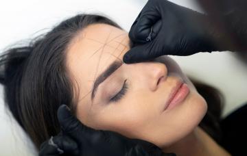 Dermatólogo examinando las cejas de una paciente