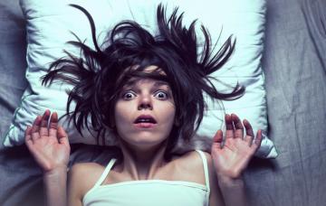 Onirofobia: cómo vencer el miedo a dormir Chica en la cama despertándose sobresaltada