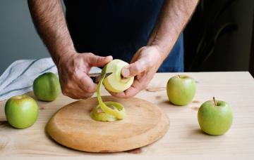 Pelar la fruta ¿es bueno o malo? Hombre pelando la piel de una manzana verde