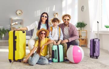 Convivencia familiar sana en las vacaciones de verano Familia de dos adultos, niño y niña con las maletas listas para el verano dentro de casa