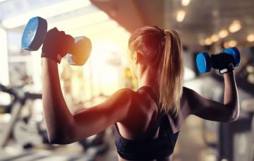 Entrenamiento de fuerza para la anorexia Mujer delgada de espaldas haciendo pesas con mancuernas