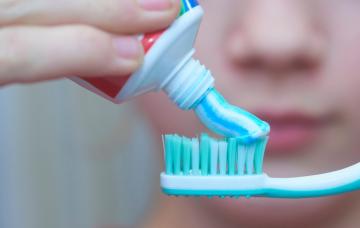 Un joven poniendo un poco de pasta de dientes sobre el cepillo dental