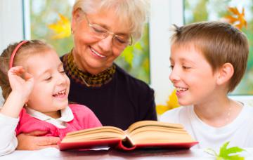 Una abuela 'au pair' lee un libro con sus 'nietos'