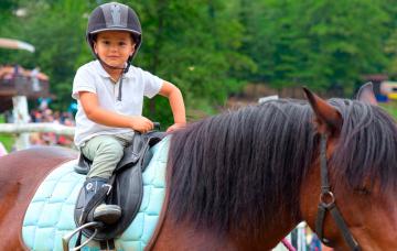Niño pequeño aprendiendo a montar a caballo
