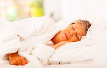 Una mujer mayor duerme en su cama