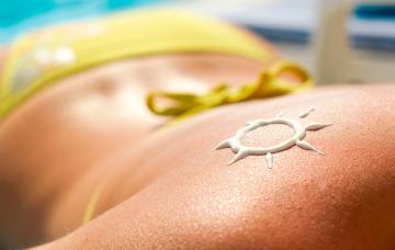 Espalda de una mujer con el dibujo de un sol hecho con crema protectora