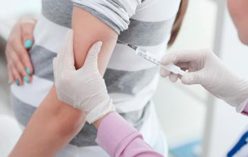 Una profesional sanitaria administra una vacuna a una embarazada