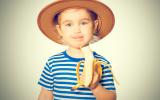 Una niña sostiene un plátano que se está comiendo