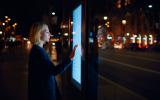Una mujer consulta un panel interactivo en una ciudad inteligente