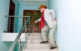 Un hombre mayor sube con dificultad las escaleras apoyado en un bastón