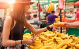 Una mujer compra plátanos en un puesto del mercado
