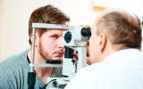 Un oftalmólogo revisa el fondo de ojo a un paciente