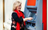 Una mujer saca dinero de un cajero automático en el exterior de la sucursal bancaria