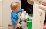 Un niño pequeño a punto de tirar un pañal sucio al cubo de basura