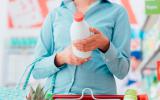 Mujer mirando la etiqueta de una botella de leche