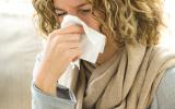 Mujer con gripe se suena la nariz