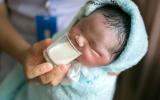 Bebé toma leche mediante un vaso