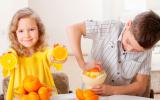 Niños exprimiendo naranjas para hacerse un zumo