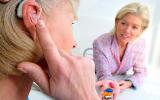 Una mujer mayor prueba un audífono en presencia de su médico