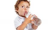 Un niño pequeño bebe agua de una botella
