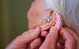 Mujer llevando audífono para reducir el riesgo de alzhéimer, depresión y caídas