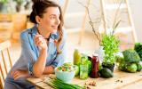Mujer joven comiendo ensalada con ingredientes frescos verdes