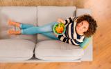 Vista superior de una mujer en el sofá comiendo dieta antiinflamatoria