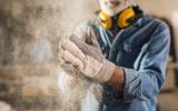 Trabajador con polvo desprendiéndose de sus guantes