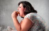 Mujer con sobrepeso comiendo una hamburguesa