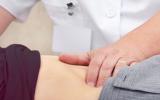 Doctor palpa el vientre de un paciente para detectar un cáncer de hígado