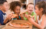 Grupo de niños comiendo pizza