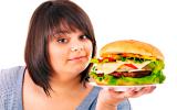Una mujer obesa sostiene una enorme hamburguesa