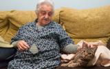 Una anciana sentada en un sofá acaricia a un gato