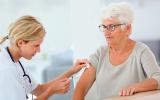 Una profesional sanitaria vacuna a una anciana