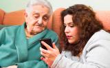 Una joven muestra la pantalla de un móvil a una anciana