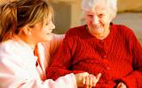 Una anciana dependiente sonríe junto a su cuidadora