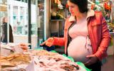 Mujer embarazada comprando pescado para tomarlo