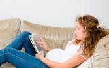 Embarazada sedentaria leyendo en el sofá