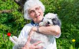 Una mujer mayor sonríe mientras sostiene a un perro en brazos