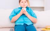 Adolescente sedentario bebe y come mientras ve la tele