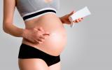 Una mujer embarazada se aplica una crema sobre la barriga