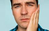 Persona con dolor derivados de bacterias que causan periodontitis