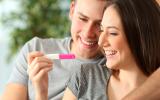 Una pareja mira sonriente un test de embarazo