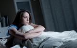 Una joven sentada en la cama tras despertarse durante la noche