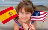 Niña sosteniendo una bandera española y otra estadounidense