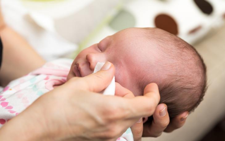 Madre aplicando pomada protectora para evitar una conjuntivitis en su bebé