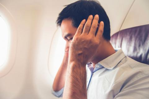 Hombre con barotrauma u oídos taponados en el avión